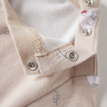Close-up of a baby outfit with buttons and organic label on a light background