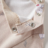 Close-up of a baby outfit with buttons and organic label on a light background