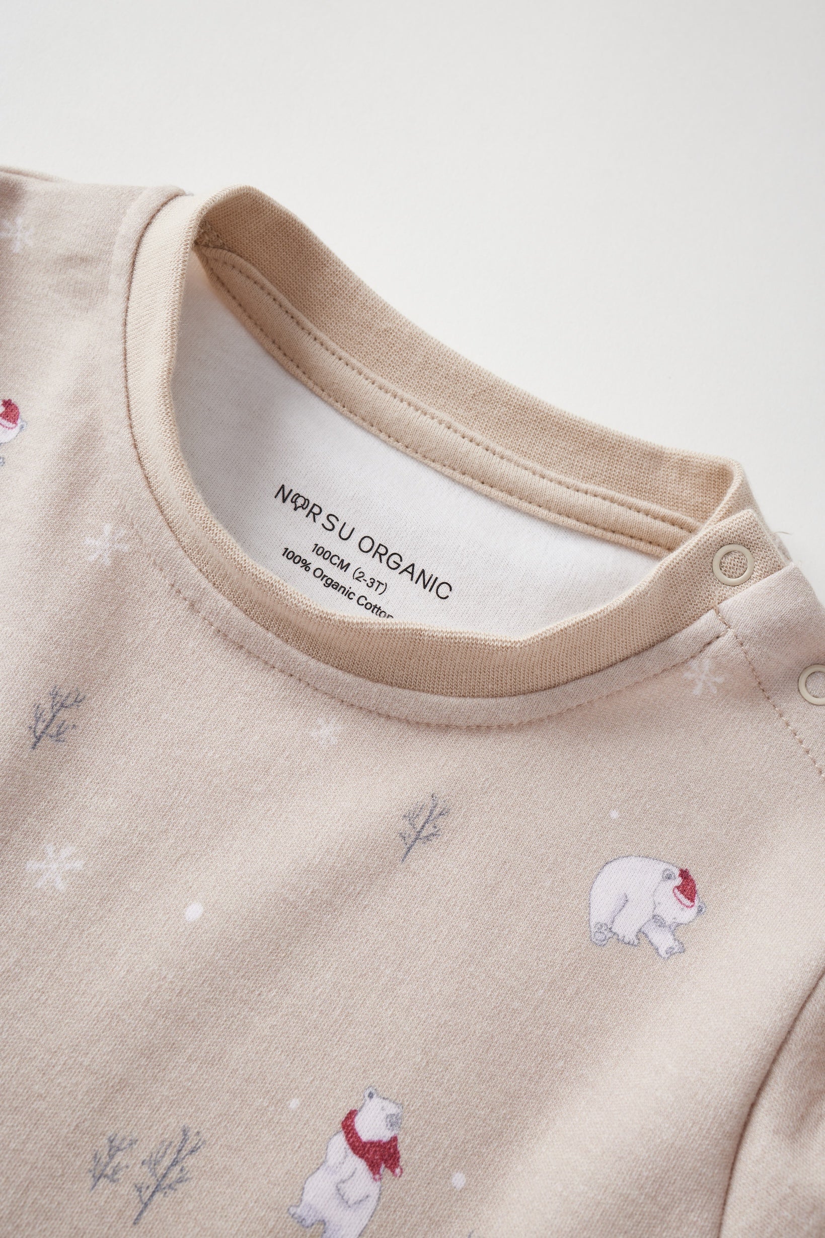 Beige baby outfit with bear illustrations and 'Norsu Organic' label on a white background