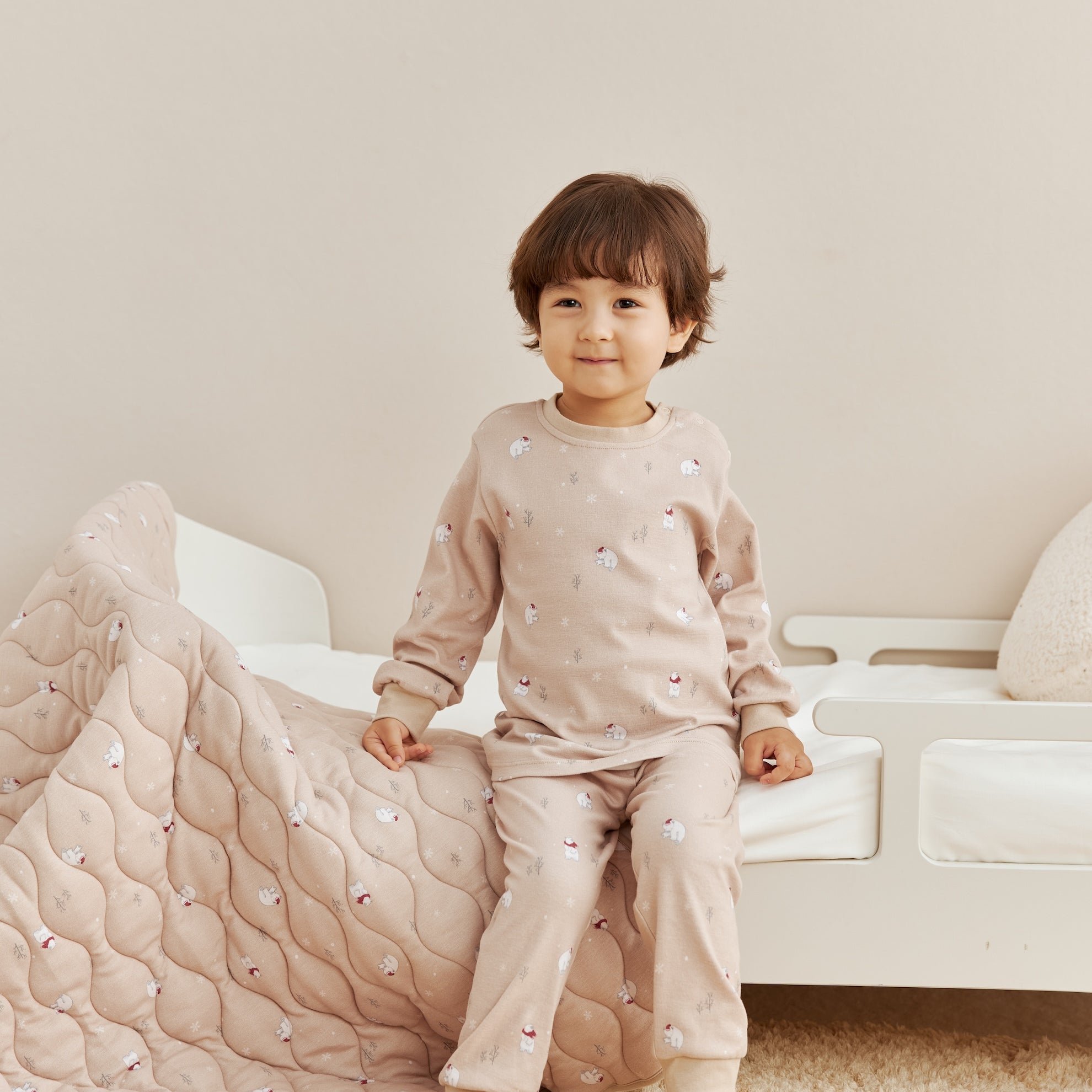 Child in polar bear pajamas sitting on a white couch with a quilted blanket