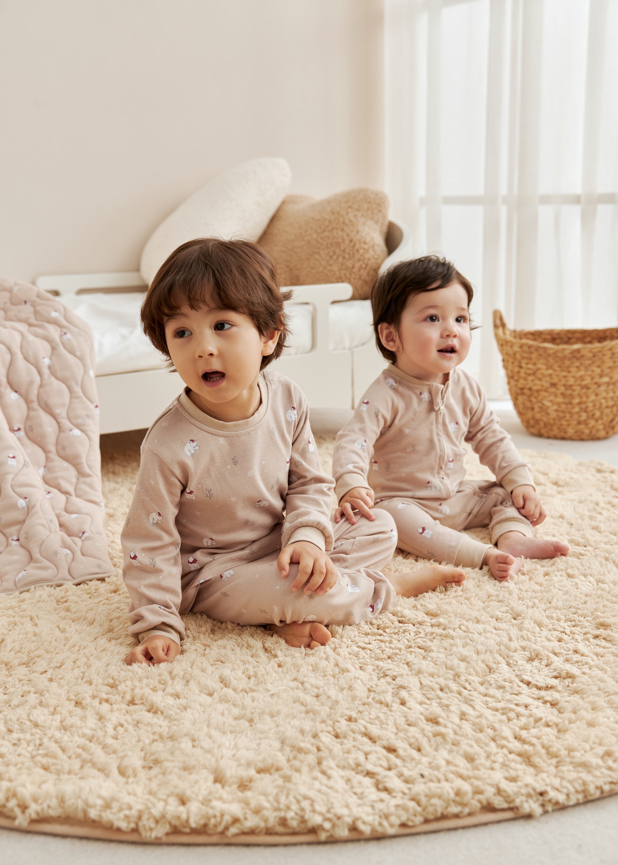 Two children sitting on a textured rug in a bright room with light-colored walls.