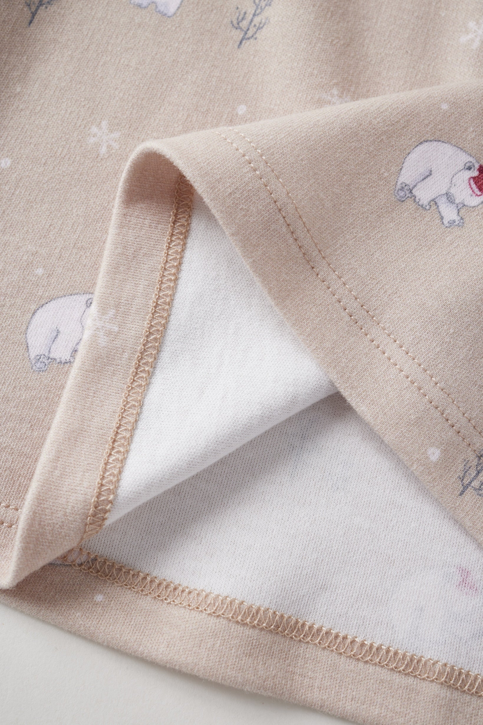 Close-up of a beige fabric with embroidered bear designs on a white background