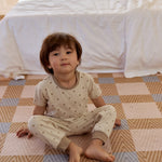 A boy in a cute dot-patterned pajama set sits on the floor