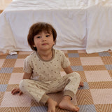 A boy in a cute dot-patterned pajama set sits on the floor