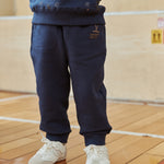 Person wearing navy blue tracksuit and white sneakers on a wooden floor.