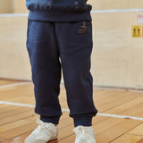 Person wearing navy blue tracksuit and white sneakers on a wooden floor.