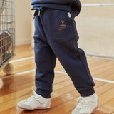 Person wearing navy tracksuit with white sneakers on a wooden floor.