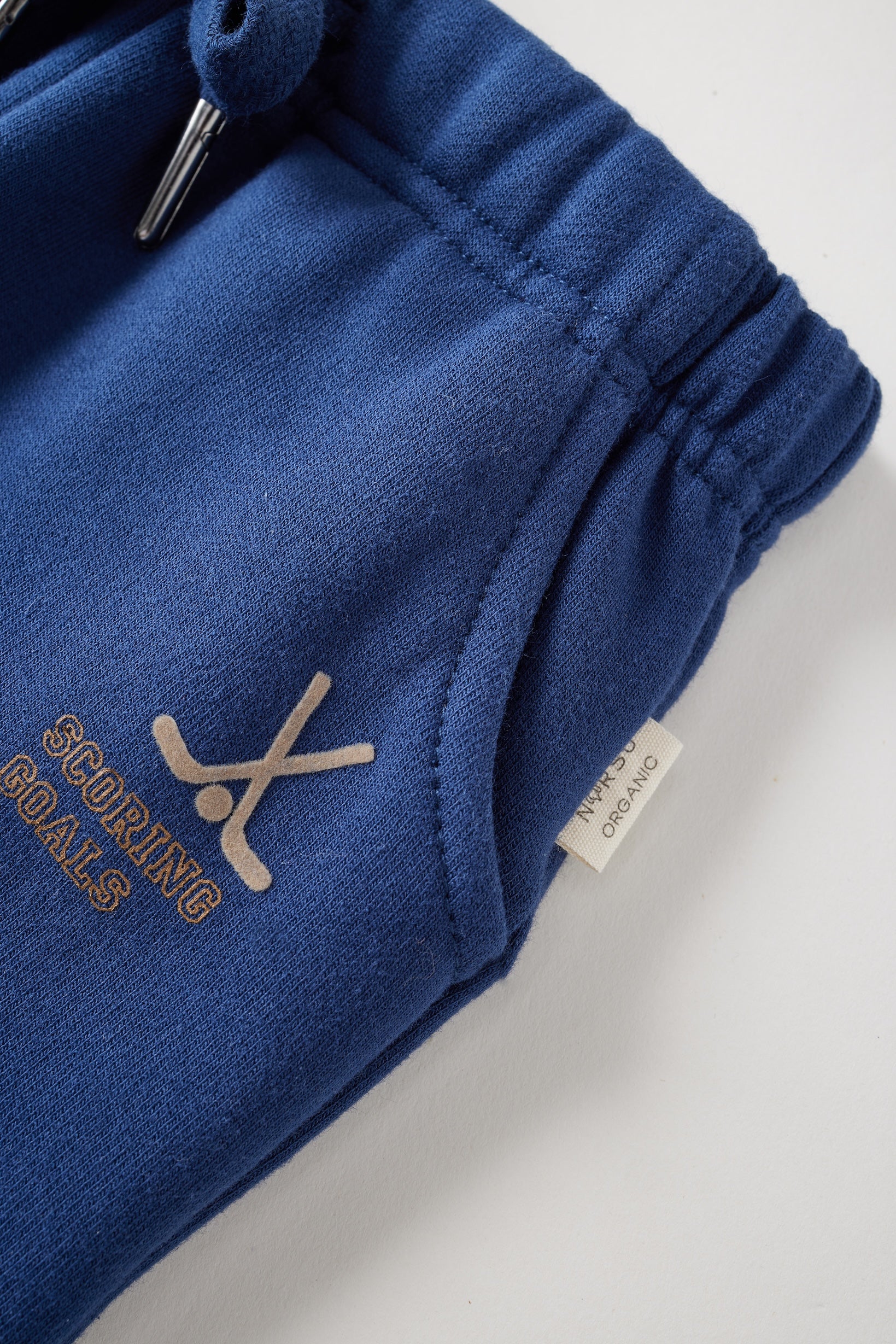 Blue sweatpants with hocket print and text on a light gray background