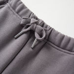 Close-up of gray sweatpants with drawstring on a light gray background