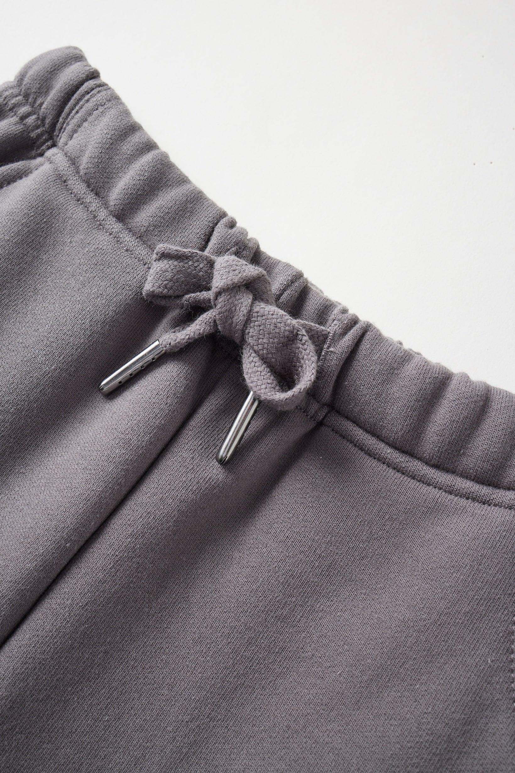 Close-up of gray sweatpants with drawstring on a light gray background