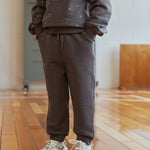 Person wearing a gray sweatshirt and pants set on a wooden floor.