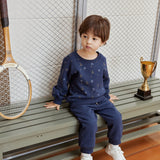 Child sitting on a bench with a tennis racket and trophy in the background