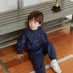 Child sitting on a wooden floor with a gold trophy in the background