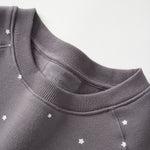 Dark gray sweatshirt with star patterns on a light gray background