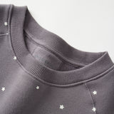 Dark gray sweatshirt with star patterns on a light gray background