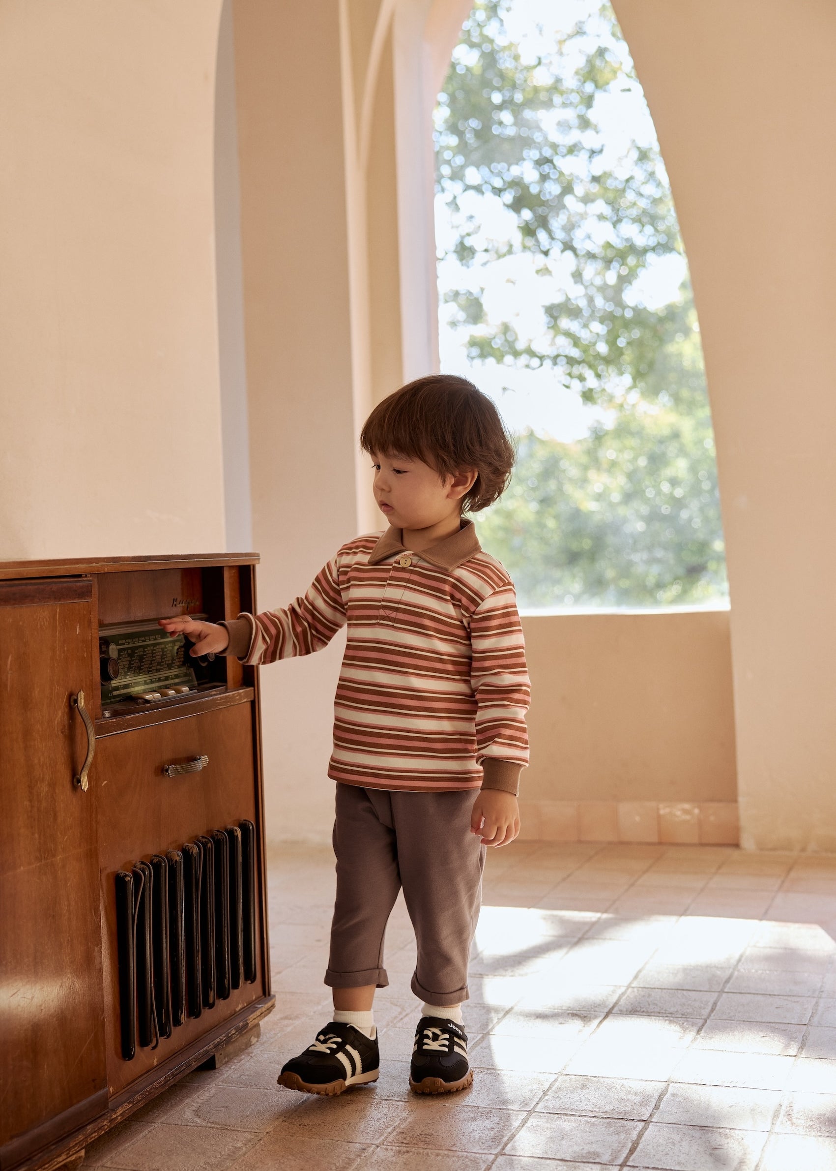  A young boy smiles while standing in front of a vintage radio, showcasing a moment of nostalgia and curiosity