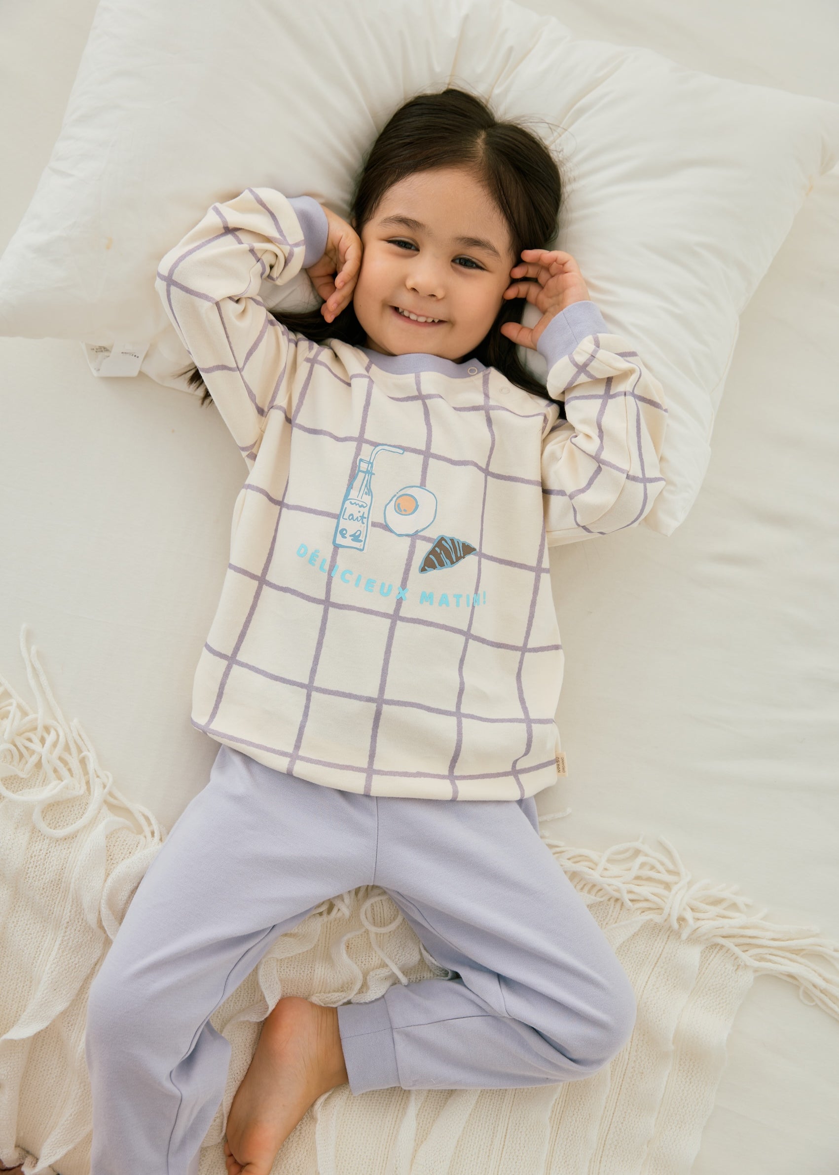 baby girl lying on the bed and wearing Organic Toddler Pajama Set-Milky