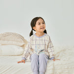 baby girl sitting on the bed and wearing Organic Toddler Pajama Set-Milky