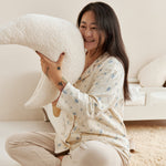 Woman sitting on a couch holding a large white pillow in a cozy living room.