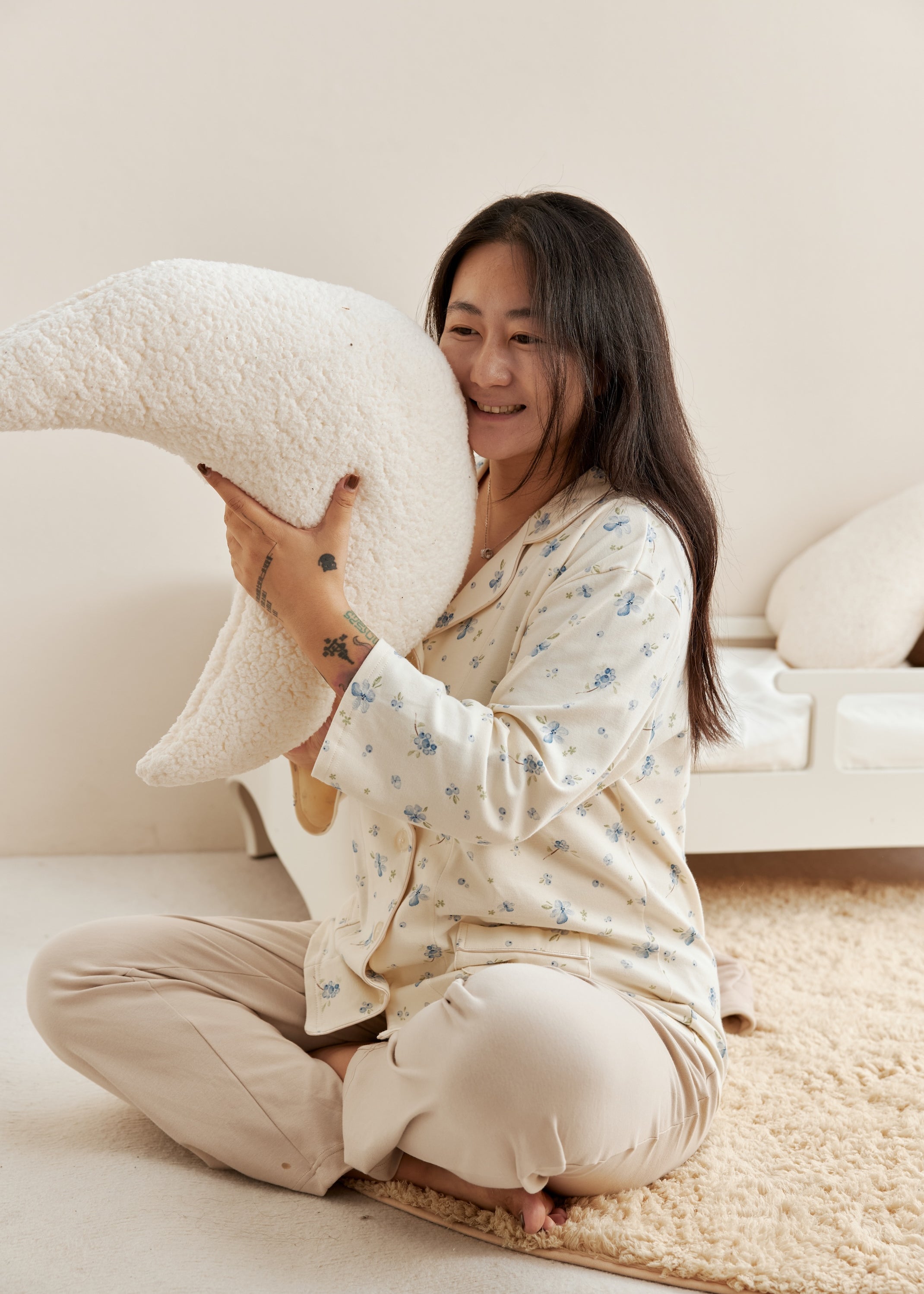 Woman sitting on a couch holding a large white pillow in a cozy living room.