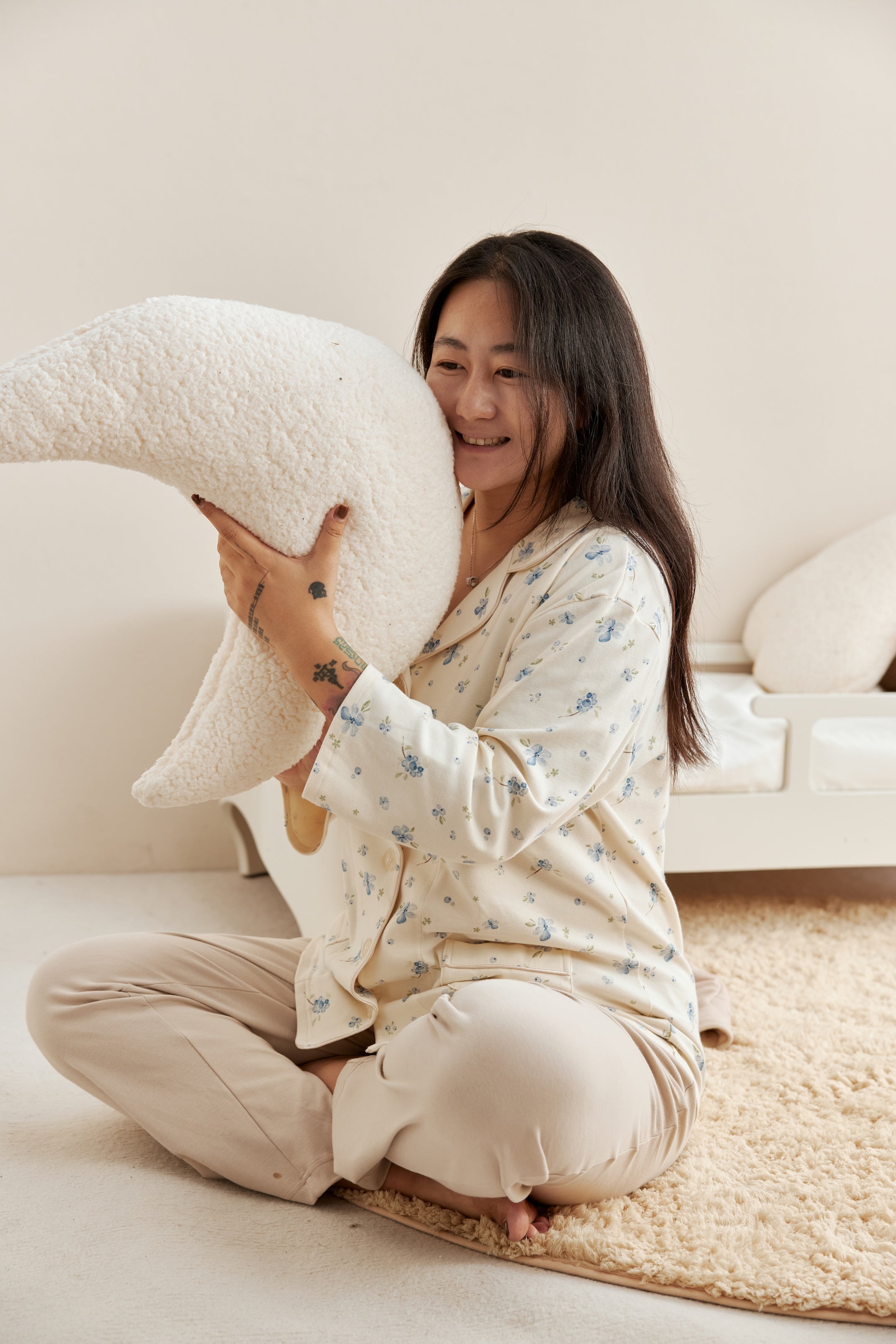 Woman sitting on a couch holding a large white pillow in a cozy living room.