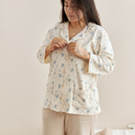 Woman wearing a floral pajama set in a cozy bedroom setting