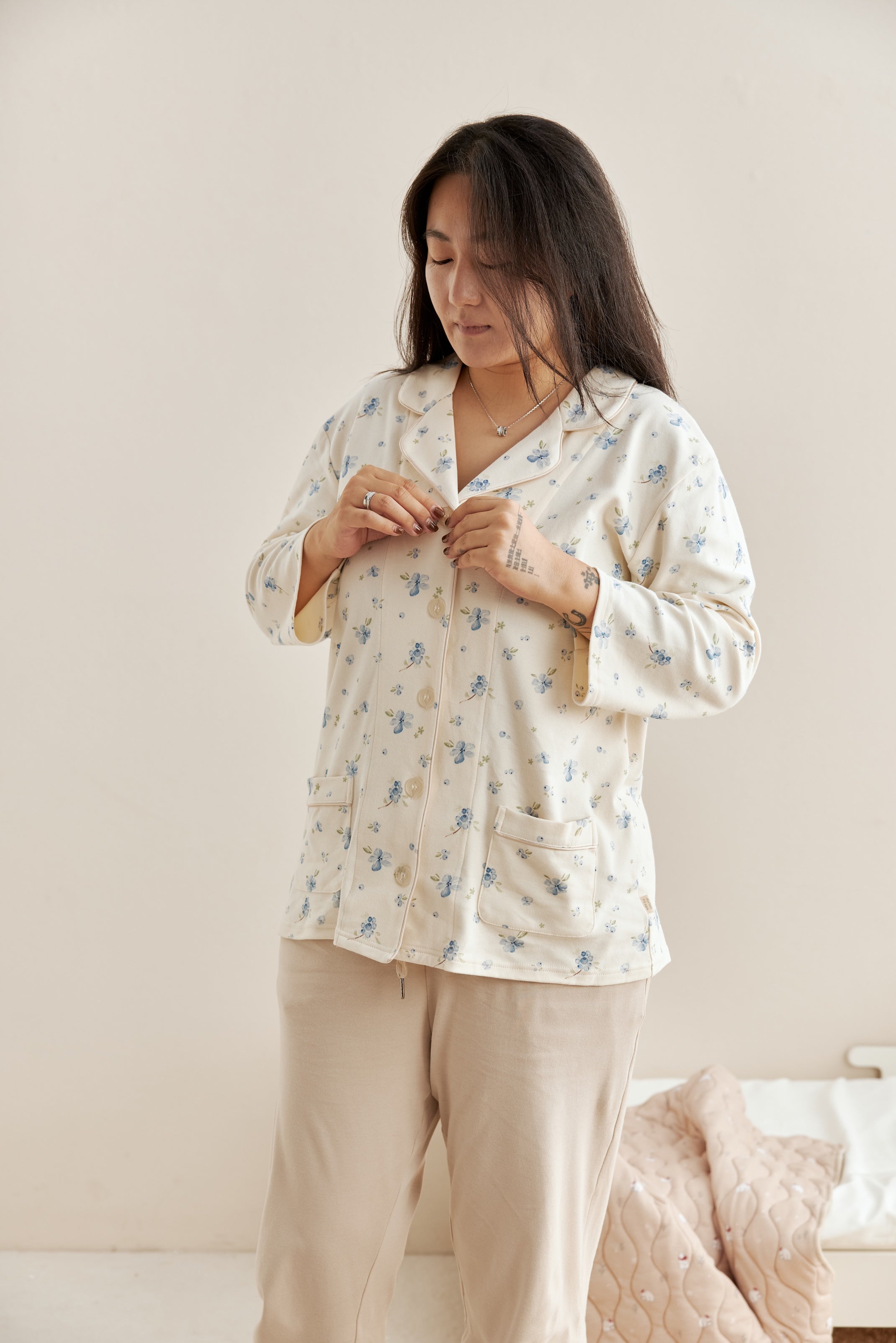 Woman wearing a floral pajama set in a cozy bedroom setting