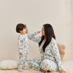 Woman and child in matching floral pajamas sitting on a beige carpet.