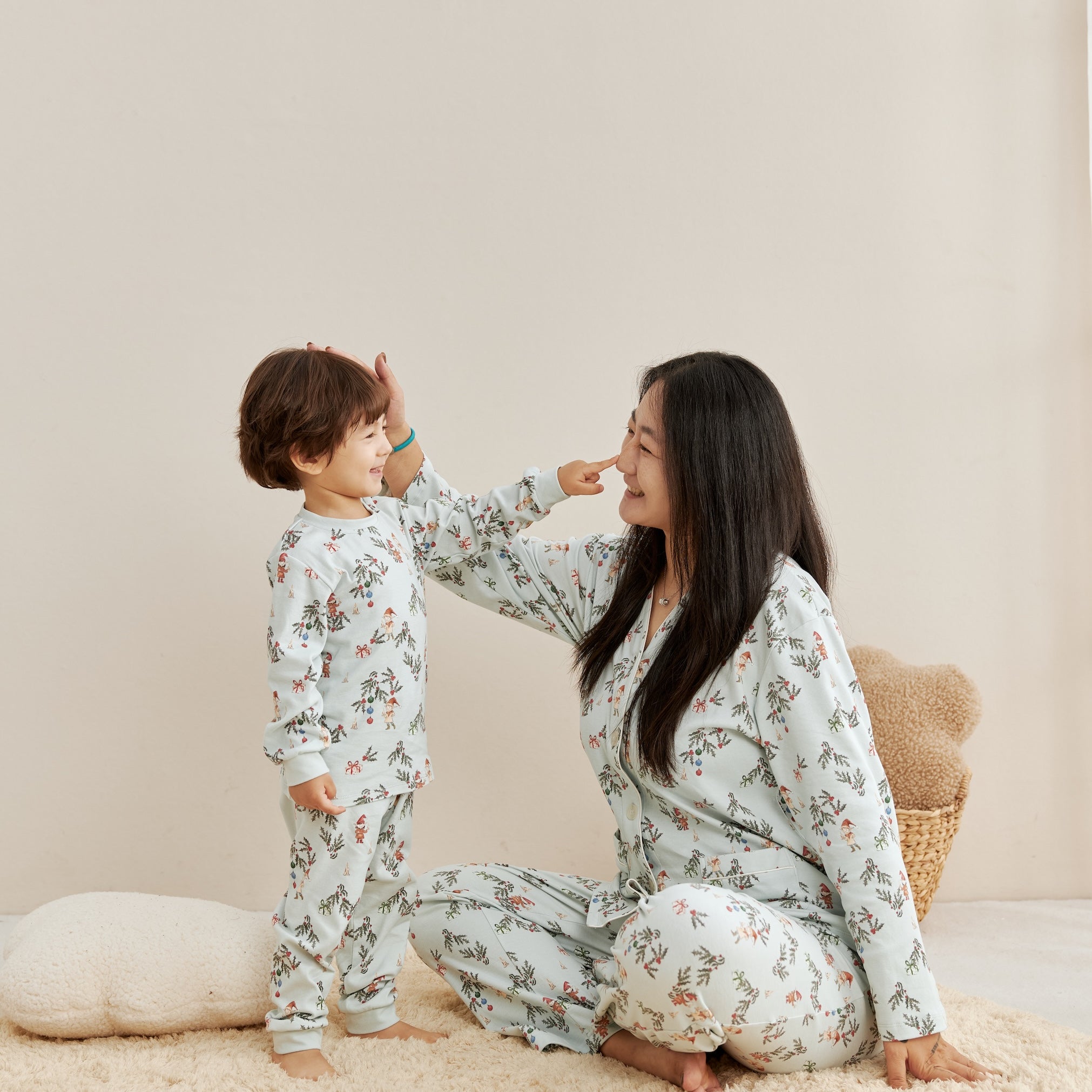 Woman and child in matching floral pajamas sitting on a beige carpet.