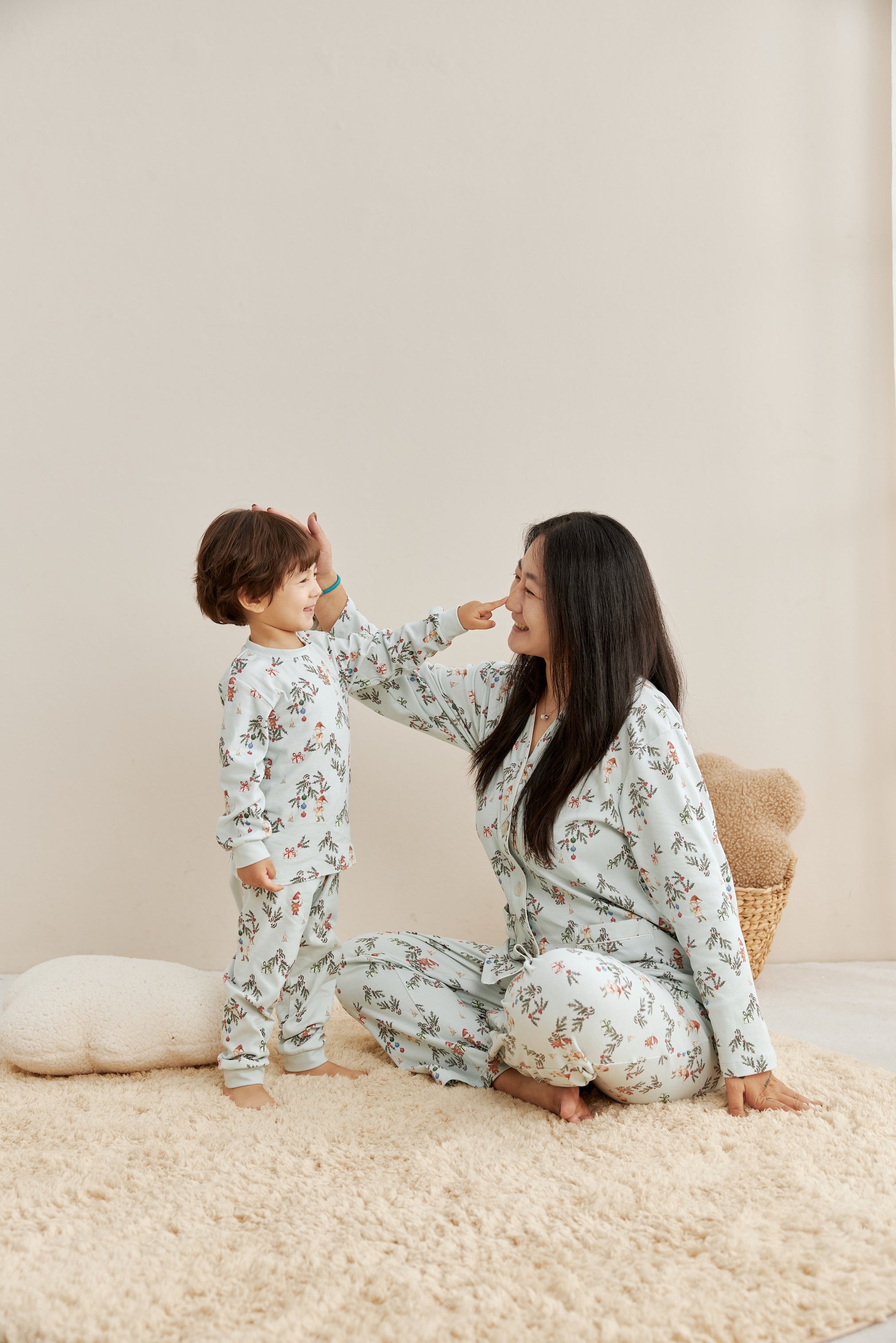 Woman and child in matching floral pajamas sitting on a beige carpet.