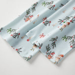 Two folded fabric swatches with a festive pattern on a light background
