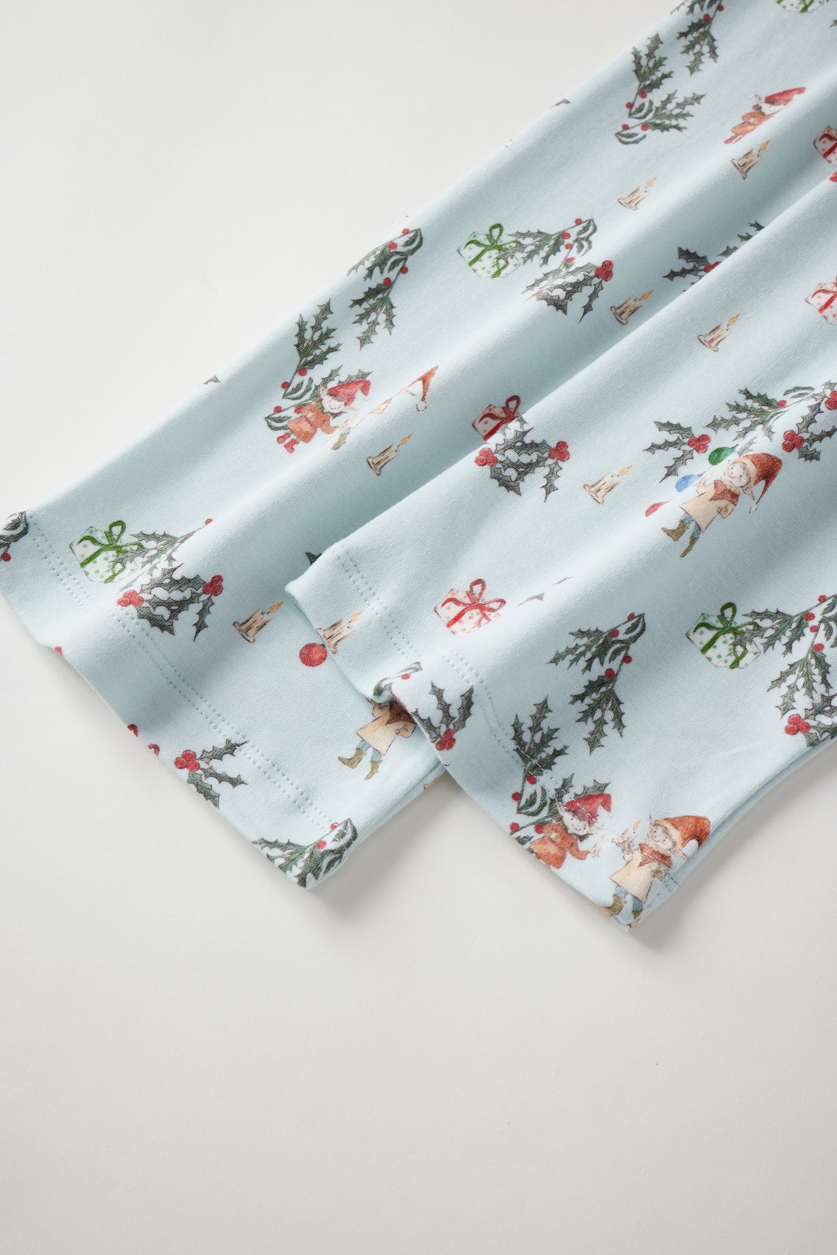 Two folded fabric swatches with a festive pattern on a light background