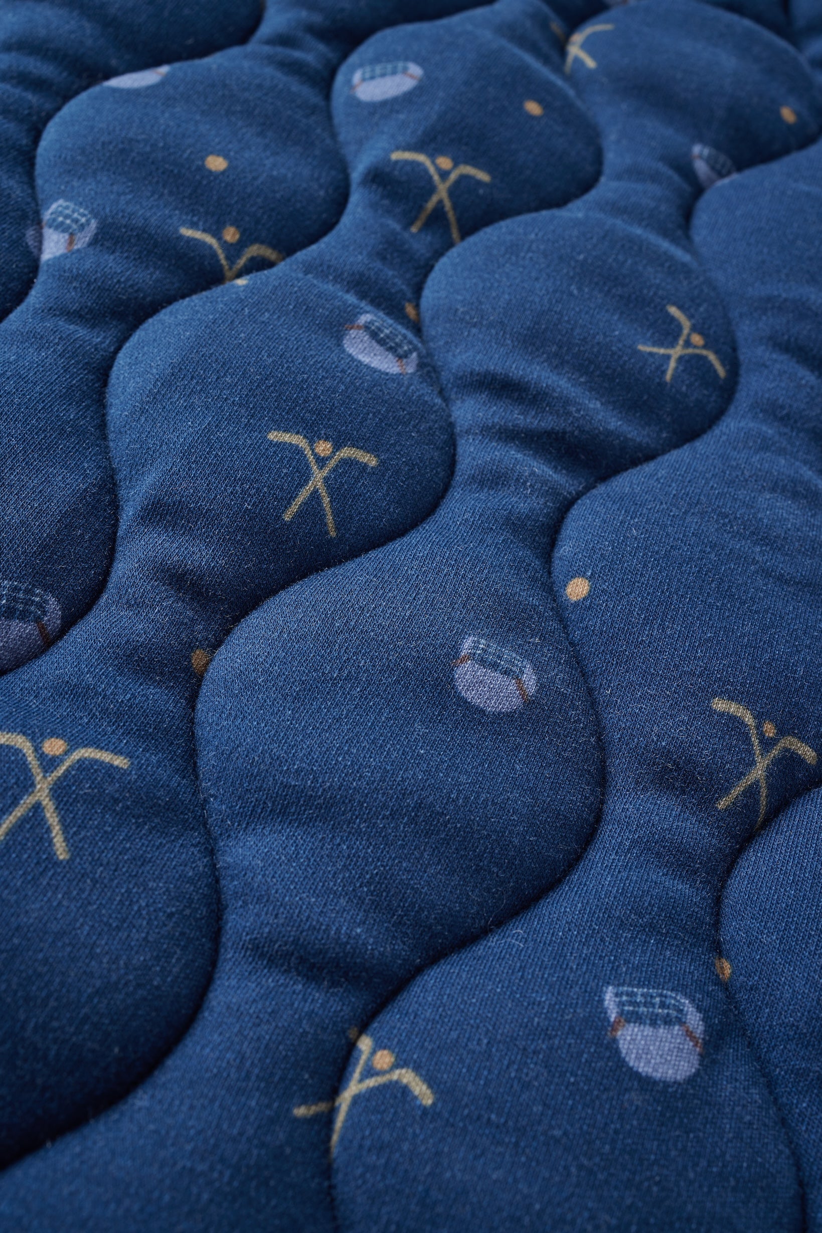 Close-up of blue blanket with embroidered designs on a textured surface