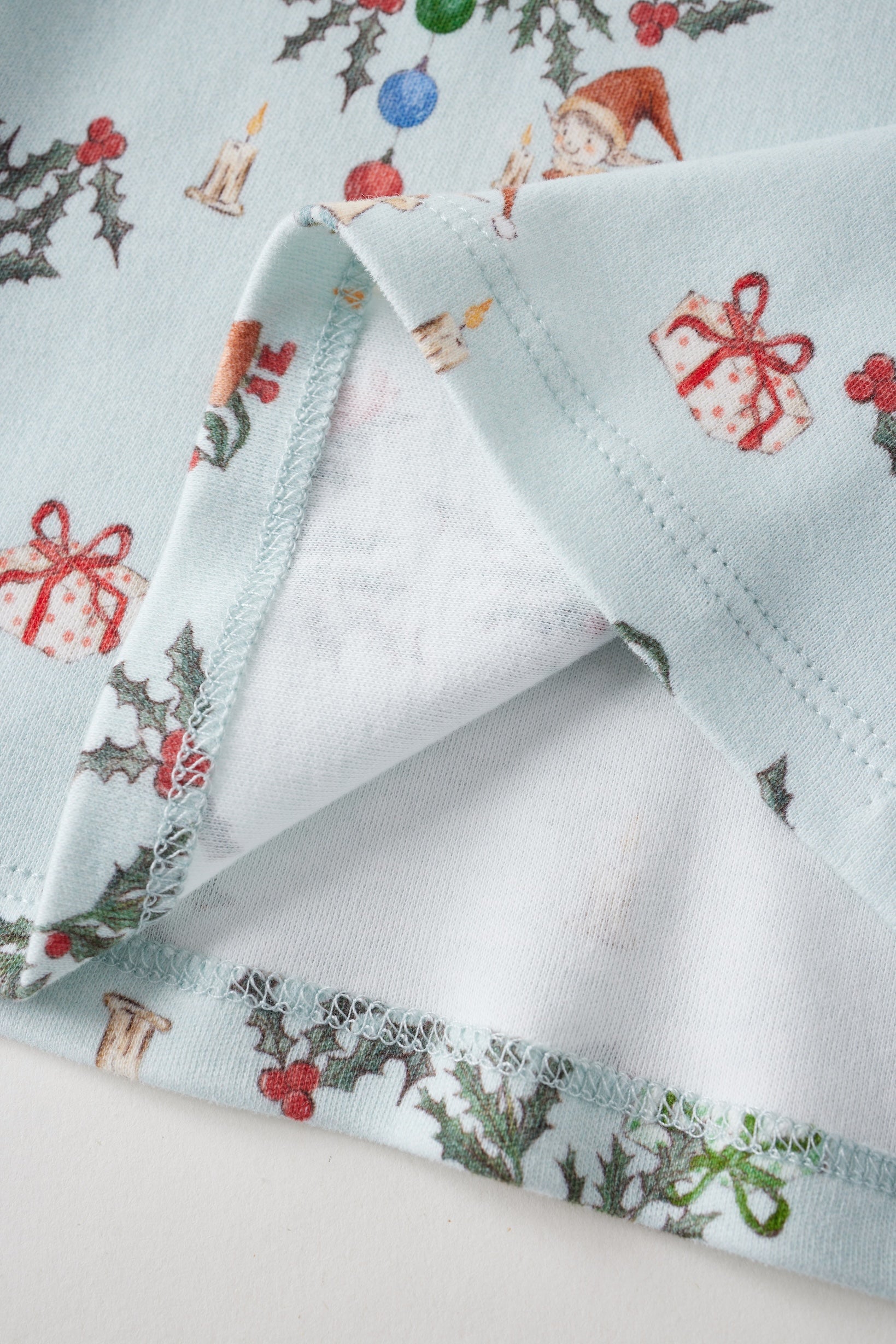 Christmas-themed fabric with reindeer, holly, and presents on a white background