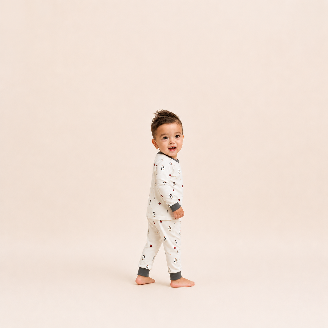 Child wearing a patterned onesie on a beige background