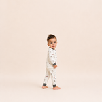 Child wearing a patterned onesie on a beige background