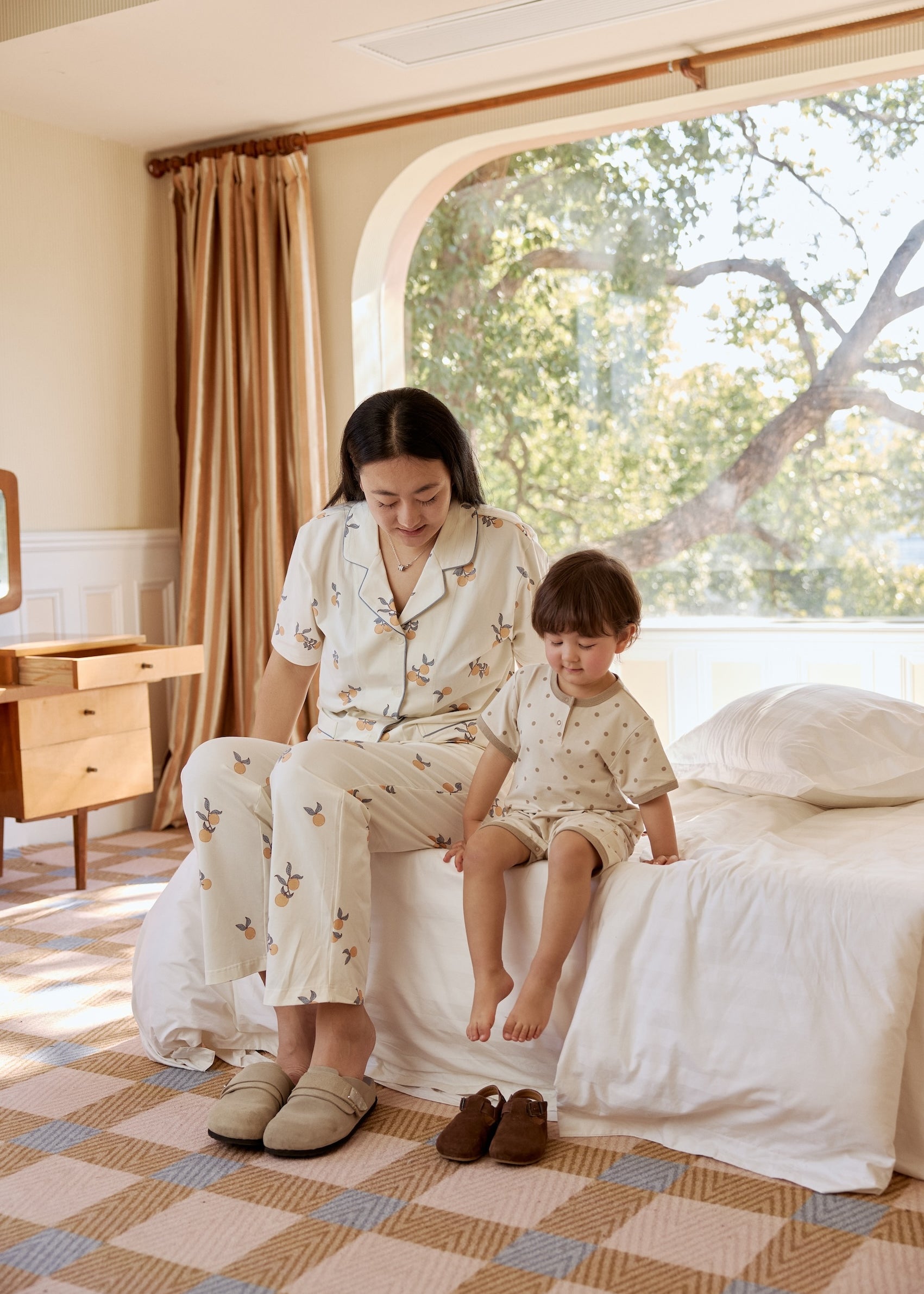 A mother and her child relax together on a cozy bed in a softly lit room, sharing a moment of warmth and comfort.