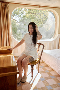 A woman relaxes in a floral bamboo lounge set, sitting comfortably on a chair in a cozy room
